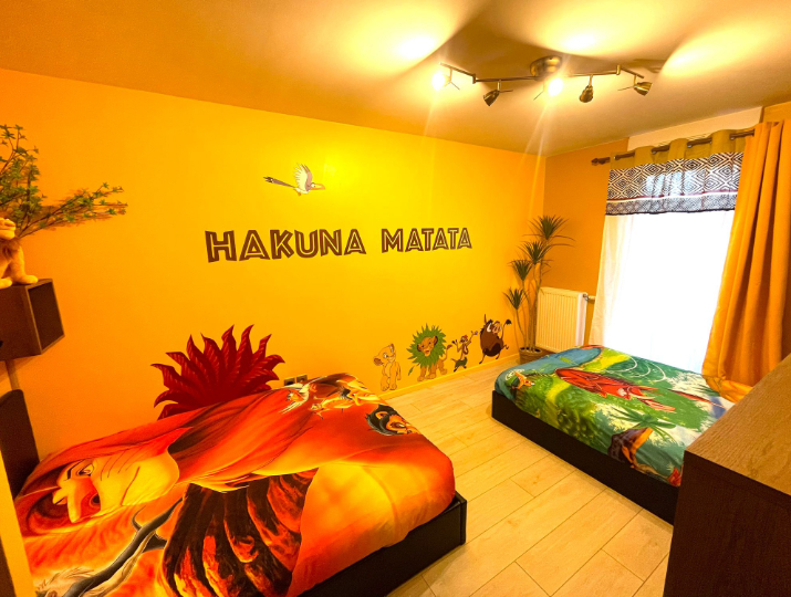 Chambre de la King Room disponible via Airbnb. Elle est entièrement décorée sur le thème du Roi Lion. On peut la célèbre phrase de ce Disney : Hakuna Matata ainsi que Simba Nala Timon et Pumba. La chambre est jaune.