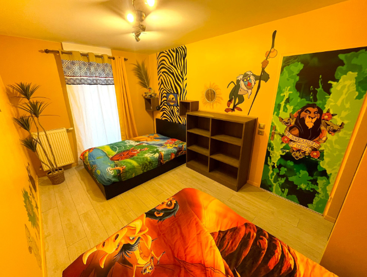 Chambre de la King Room disponible via Airbnb. Elle est entièrement décorée sur le thème du Roi Lion. On peu y voir des personnages emblématique tel Rafiqui ou Scar. La chambre est jaune. Les draps des lits dépeigne des scènes du Roi Lion.